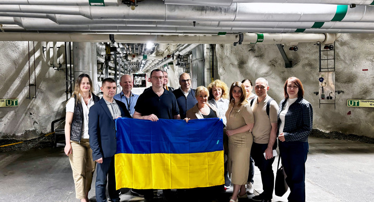 Gruppfoto i ett utrymme med många rör i taket.