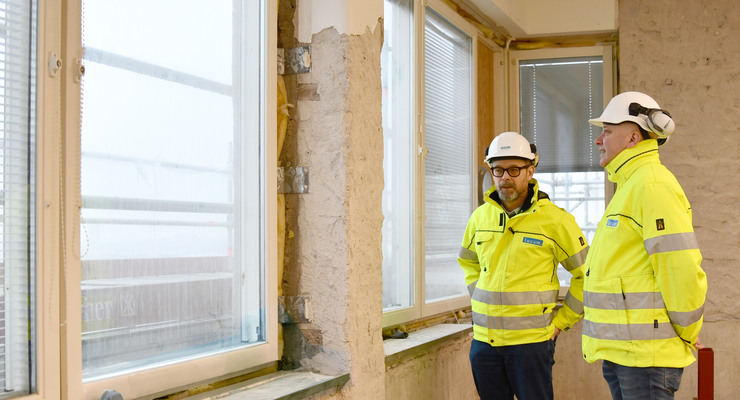 Några män som står bredvid varandra nära ett fönster