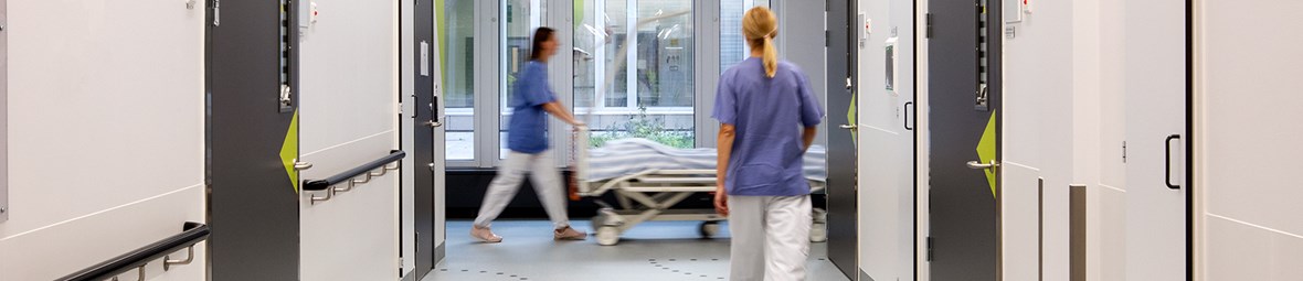 Sjukårdspersonal på avstånd går i sjukhuskorridor