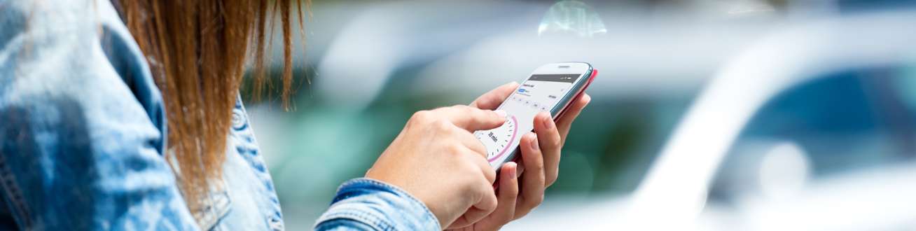 En kvinna ska starta parkering på sin mobiltelefon.