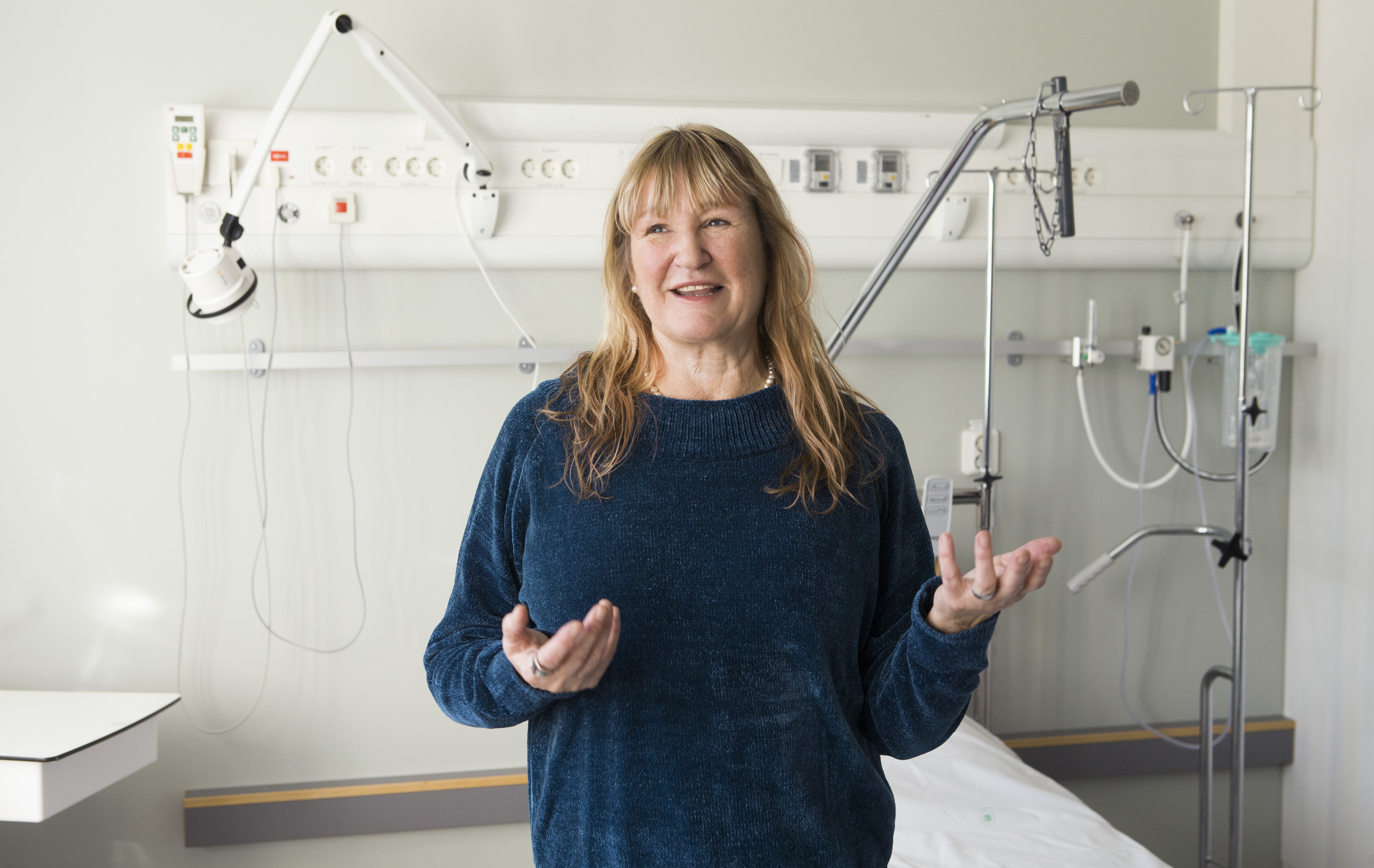 Lise-Lotte står framför en vårdpanel i ett vårdrum.