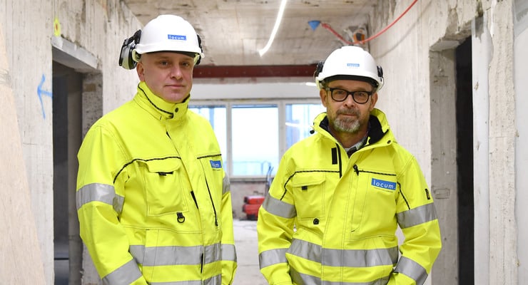 Två män i gula jackor och skyddshjälmar