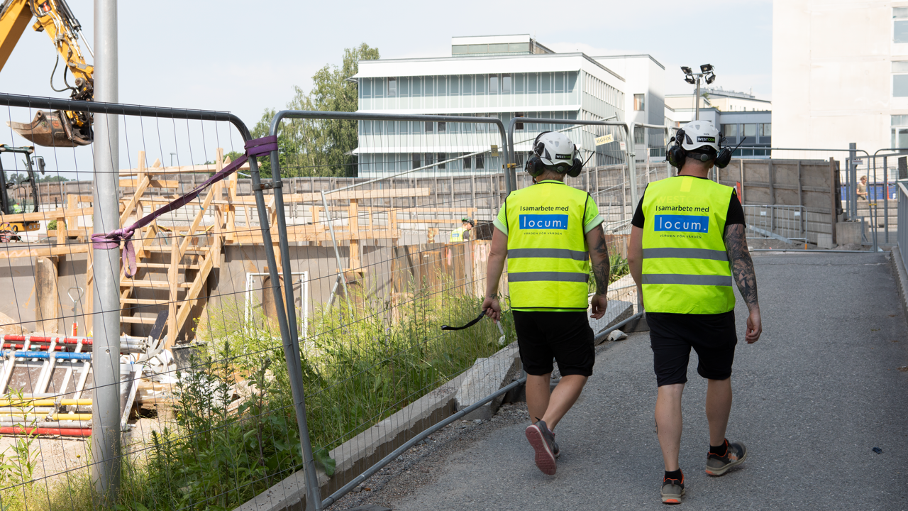 Tv&aring; byggarbetare fotade bakifr&aring;n n&auml;r de g&aring;r vid Danderyds sjukhus.