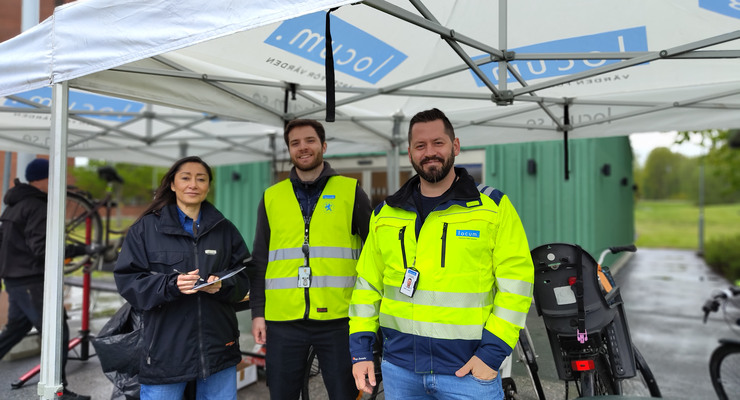 Tre Locummedarbetare står under ett tält med cyklar i bakgrunden.