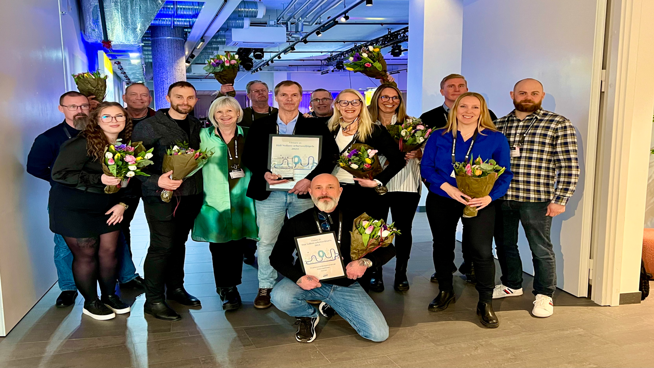 Grupp med män och kvinnor med blommor i handen som mottagit Håll Nollans arbetsmiljöpris.