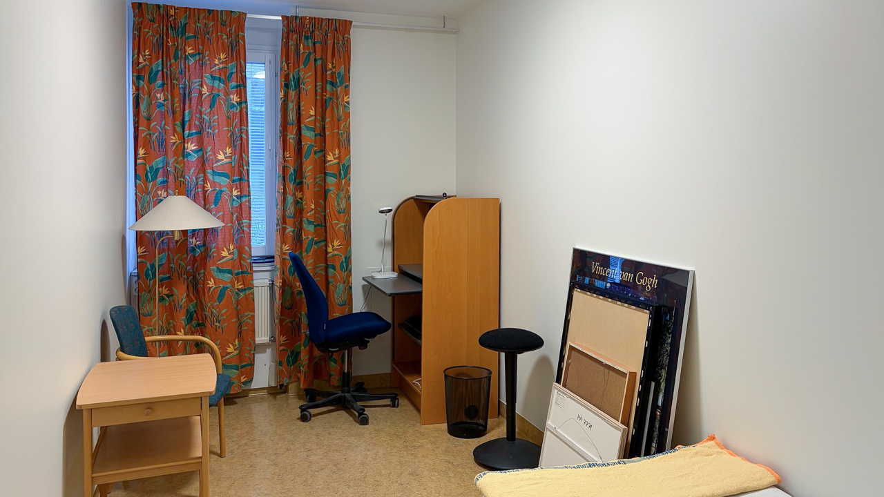 Ett rum med en säng, ett skrivbord, en stol och ett fönster.