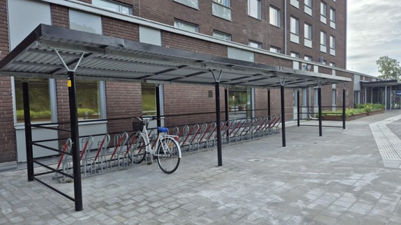En cykel står parkerad vid cykelställ bredvid sjukhusbyggnad.