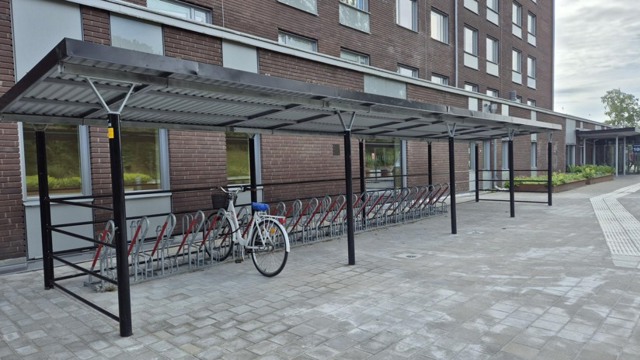 En cykel står parkerad vid cykelställ bredvid sjukhusbyggnad.