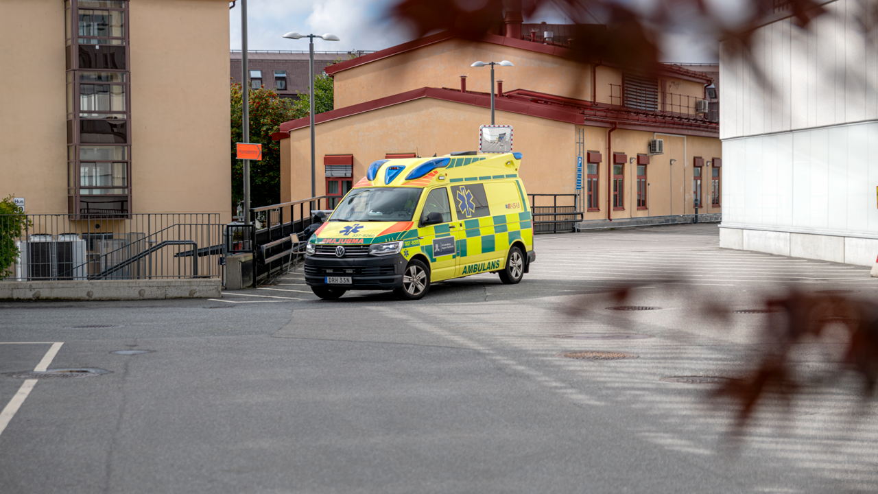 En ambulans parkerad p&aring; en parkeringsplats bredvid en byggnad.
