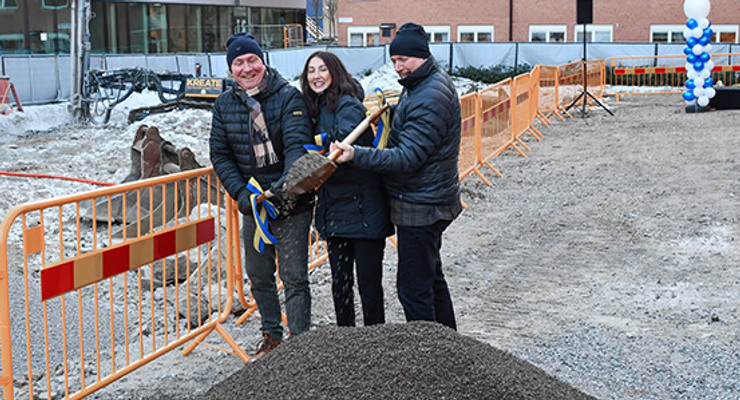 Tre personer håller i en spad och gräver i en grushög tillsammans som ligger framför dem. 