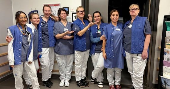 En grupp medarbetare från Ortopedmottagningen vid Danderyds sjukhus framför ett nedsläckt rum.