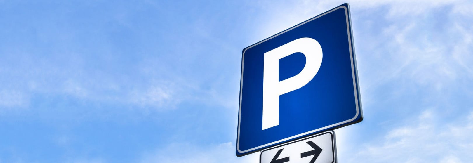 Parkeringsskylt och blå himmel.