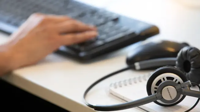 Hand på tangentbod och headset.