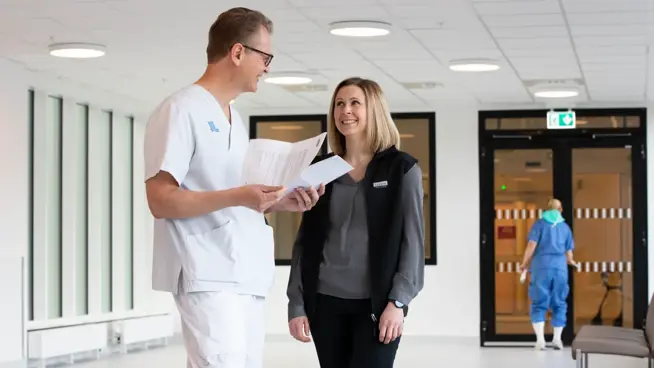 En läkare och en förvaltare pratar med varandra i en korridor.