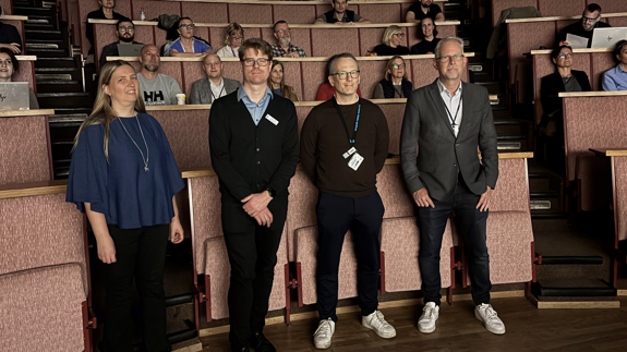 En grupp människor som står framför en föreläsningssal.