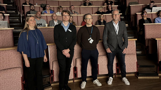 En grupp människor som står framför en föreläsningssal.