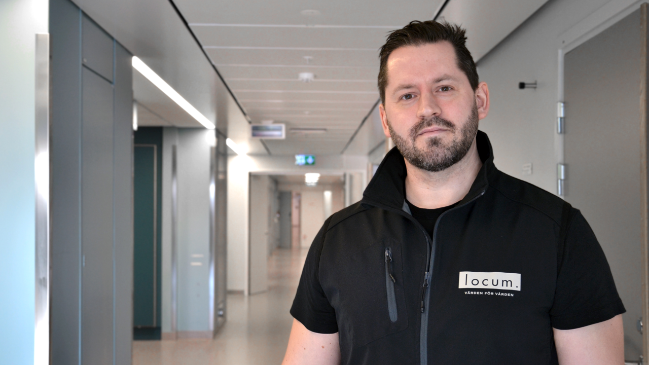En man i svart Locumv&auml;st st&aring;r i en sjukhuskorridor.
