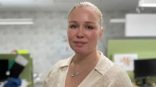 Michaela står i ett kontorslandskap och ler mot kameran. 