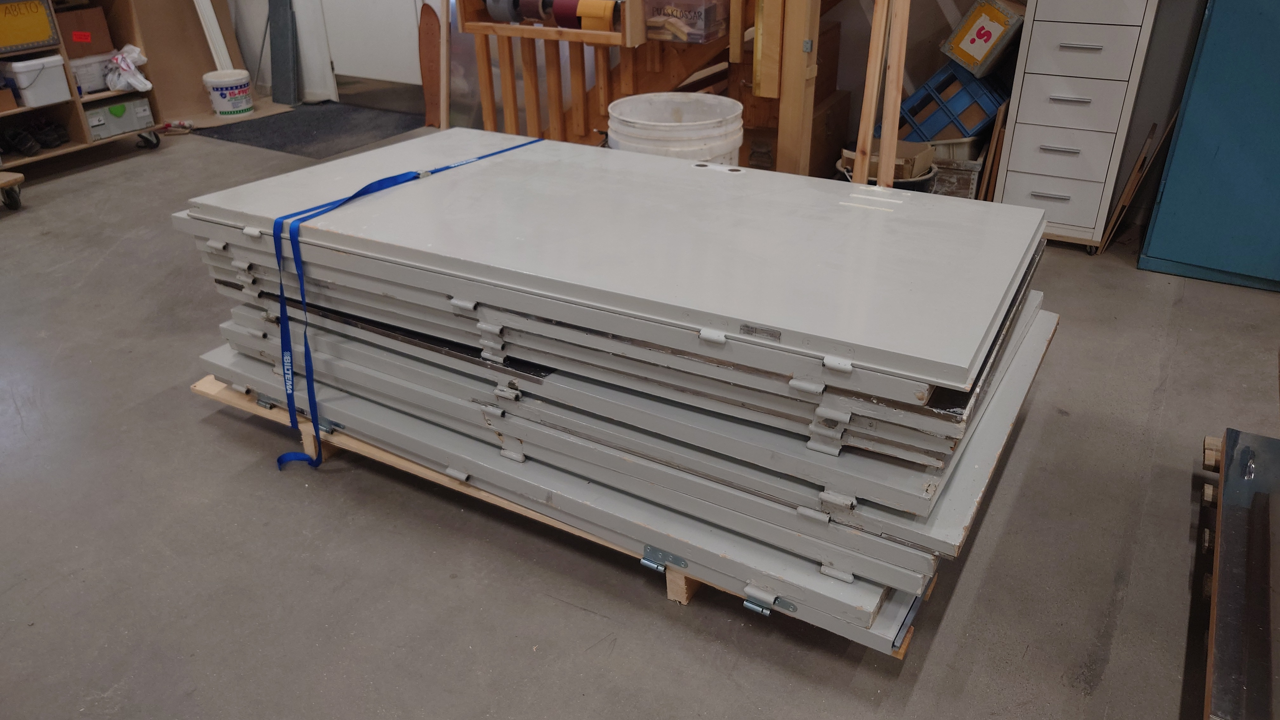 En bild av de upphittade dörrarna. De är lastade på varandra på en pall med spännen.