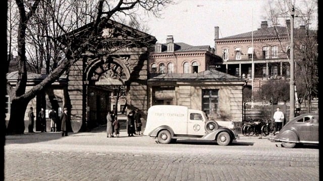 Ingång till Serafenområdet med parkerade bilar och människor som står utanför.