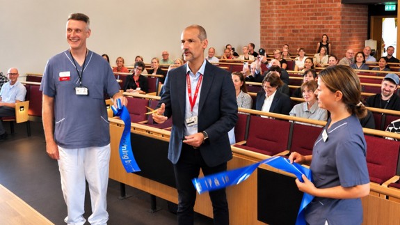 Sjukhusdirektören klipper band tillsammans med två medarbetare från vården