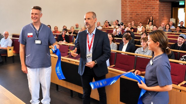 Sjukhusdirektören klipper band tillsammans med två medarbetare från vården