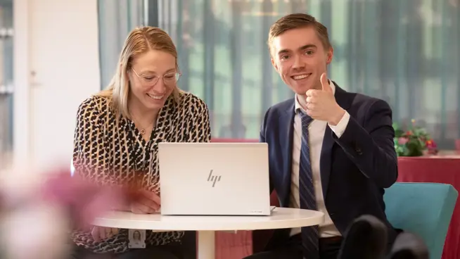 Kvinnlig och manlig medarbetare sitter vid bord med dator på.