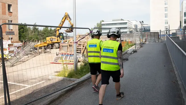 Två byggarbetare fotade bakifrån när de går vid Danderyds sjukhus.