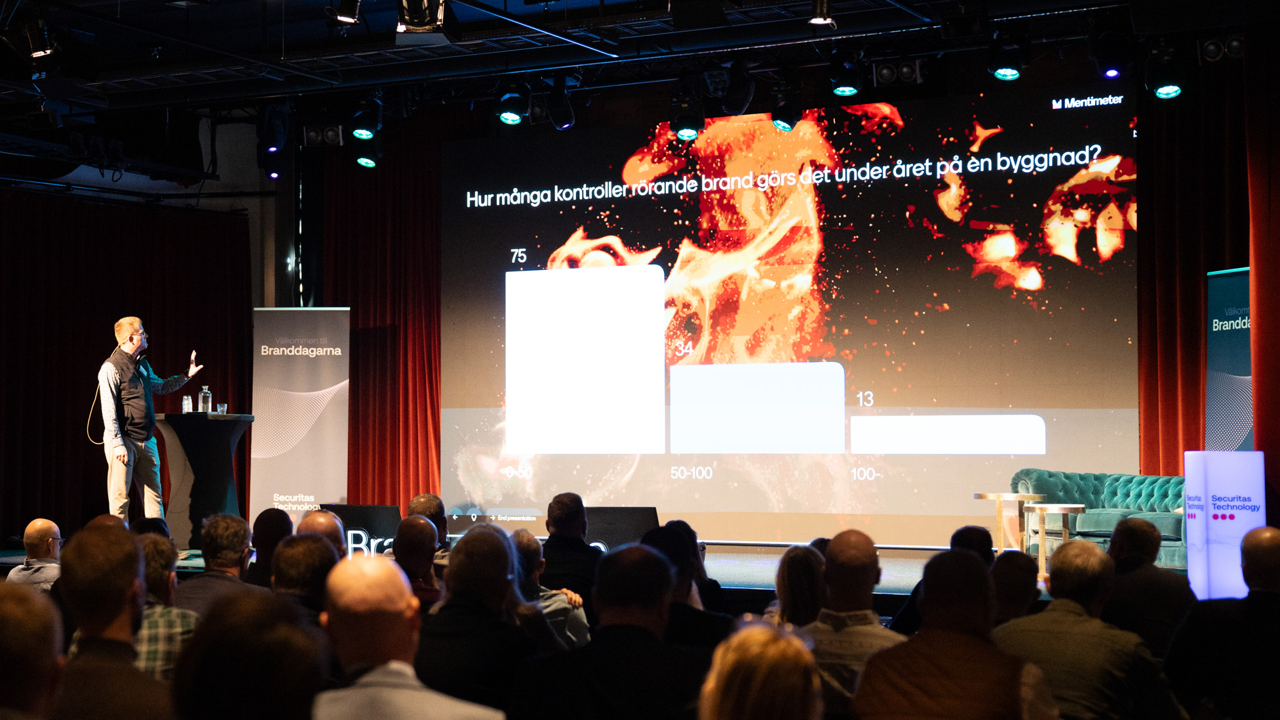 Man st&aring;r och f&ouml;rel&auml;ser p&aring; scen med publik.