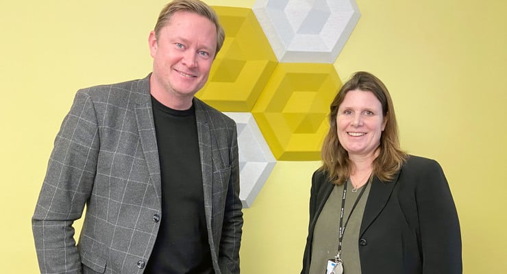 Christer Wickberg och Caroline Kvillström Brand  står i ett rum med gul vägg.