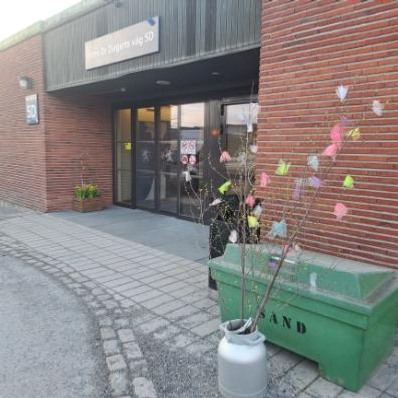 Påskliljor och påskris med fjädrar utanför sjukhusentré.