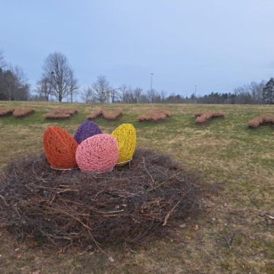 Stort fågelbo på gräsmatta med färgglada påskägg.