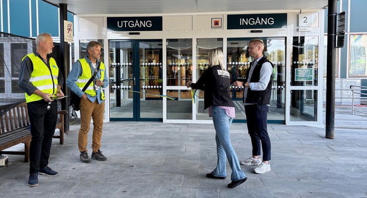 En person klipper ett band under invigning av nya entrédörrar vid Danderyds sjukhus.