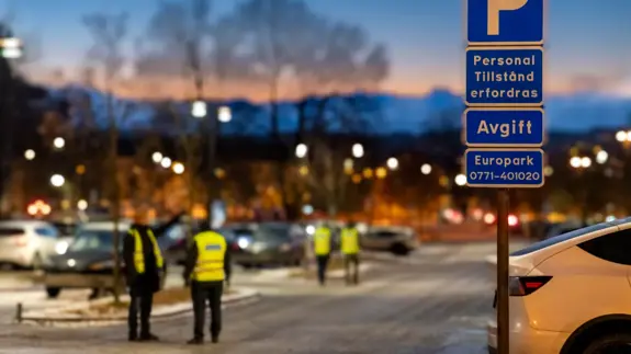En grupp människor som står bredvid en parkeringsskylt.