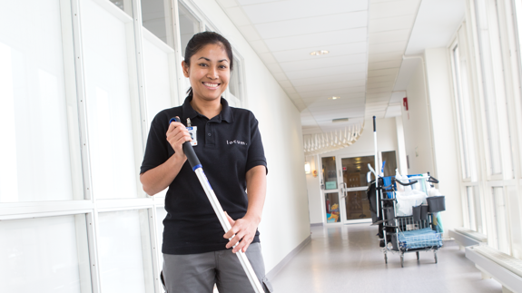 Kvinnlig lokalvårdare i sjukhuskorridor.