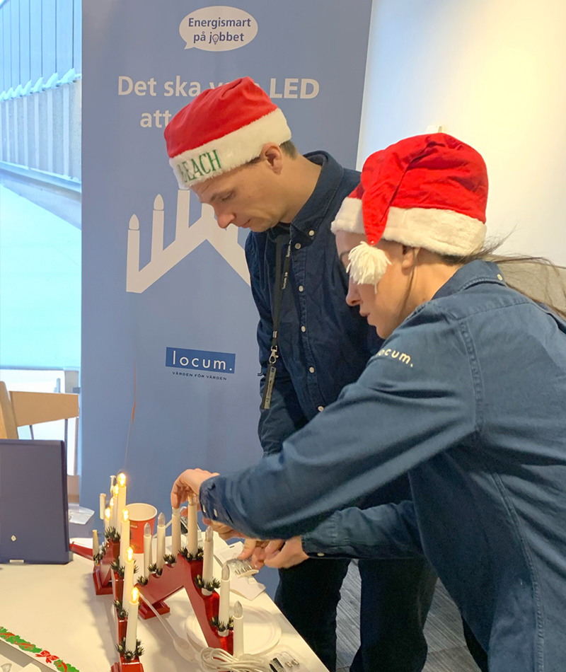 Två Locummedarbetare skruvar på LED-ljuskällor på adventsljusstakar.