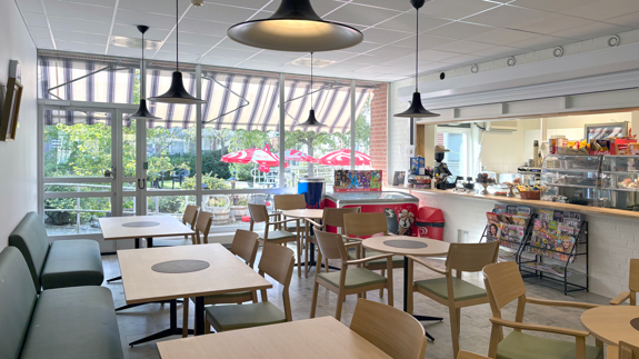 Café med bord, stolar och en disk. Stora fönster mot innergården.