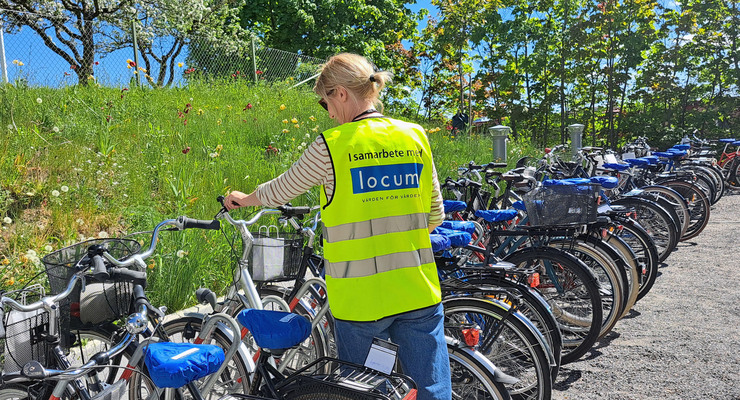 En kvinna som står bredvid ett gäng cyklar.