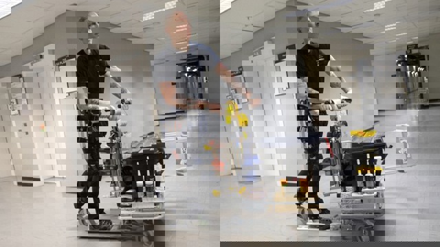 Driftpersonal åker på cykelscooter inne i en korridor.