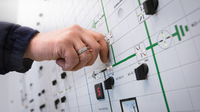 En person trycker på knappar på en vägg.