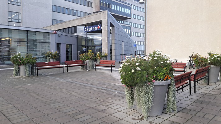 Bänkar och prunkande blomkrukor framför entrén till akutmottagningen på Södersjukhuset.
