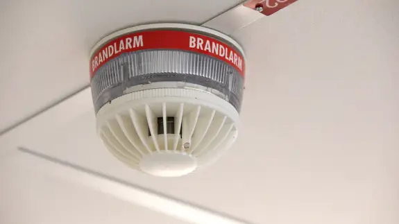 En närbild av ett brandlarm med en varningsskylt på.