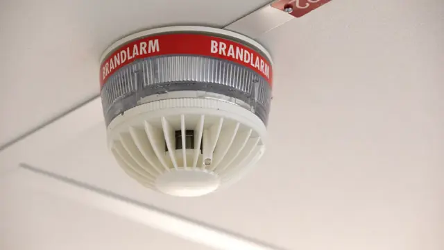 En närbild av ett brandlarm med en varningsskylt på.