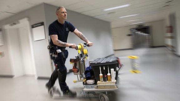 Driftpersonal som åker på en sparkcykel i en sjukhuskorridor.