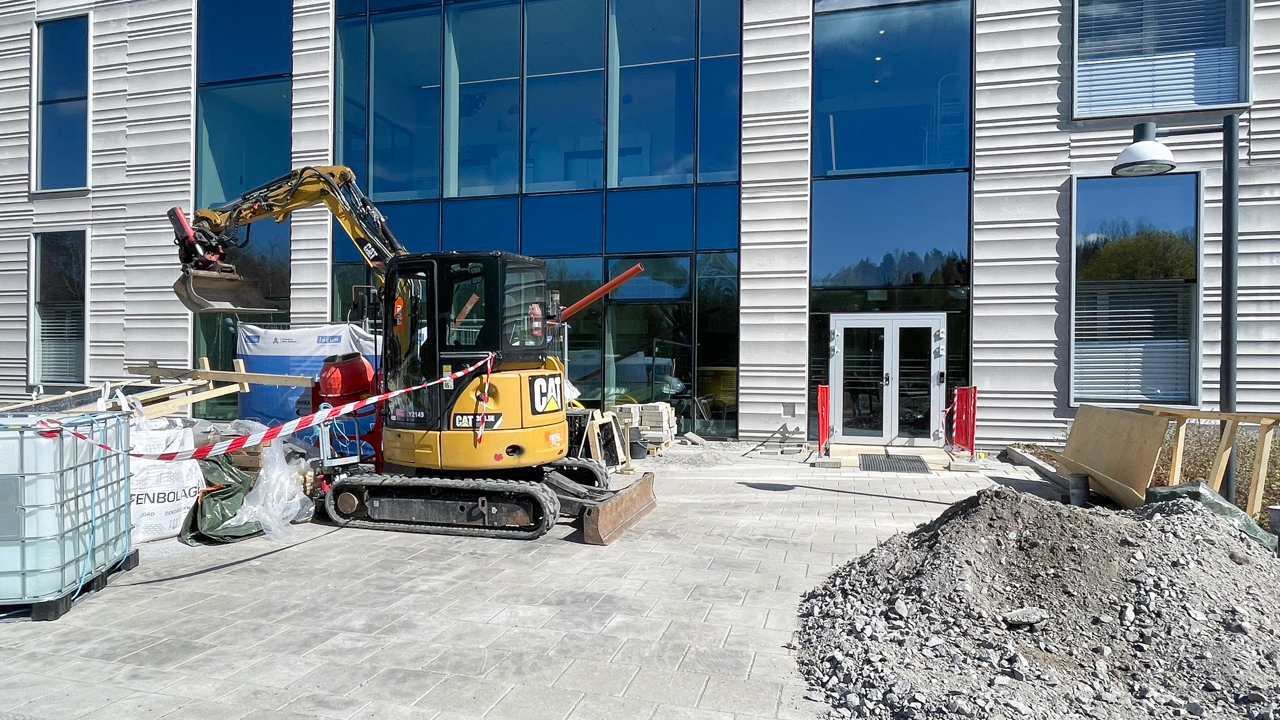 En bulldozer st&aring;r parkerad framf&ouml;r en stor byggnad.