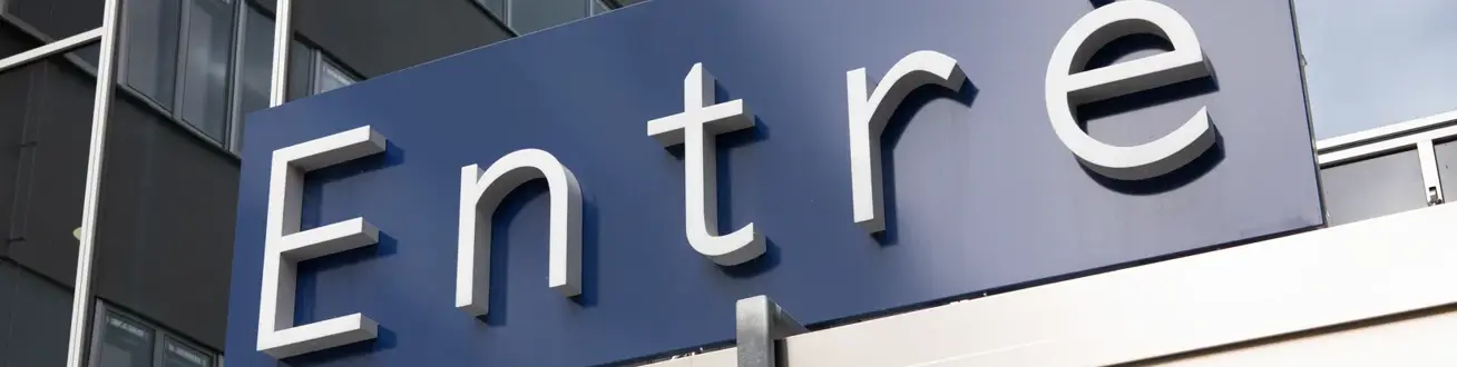 En blå skylt med texten entre på en byggnad.