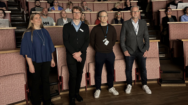 En grupp människor som står framför en föreläsningssal.