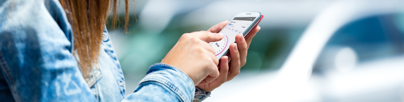 En kvinna ska starta parkering på sin mobiltelefon.