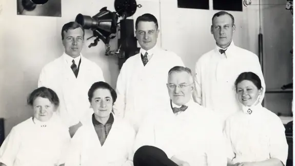 Sjuk personer  i sjukhuskläder, fyra sitter och tre står uppradade bakom.