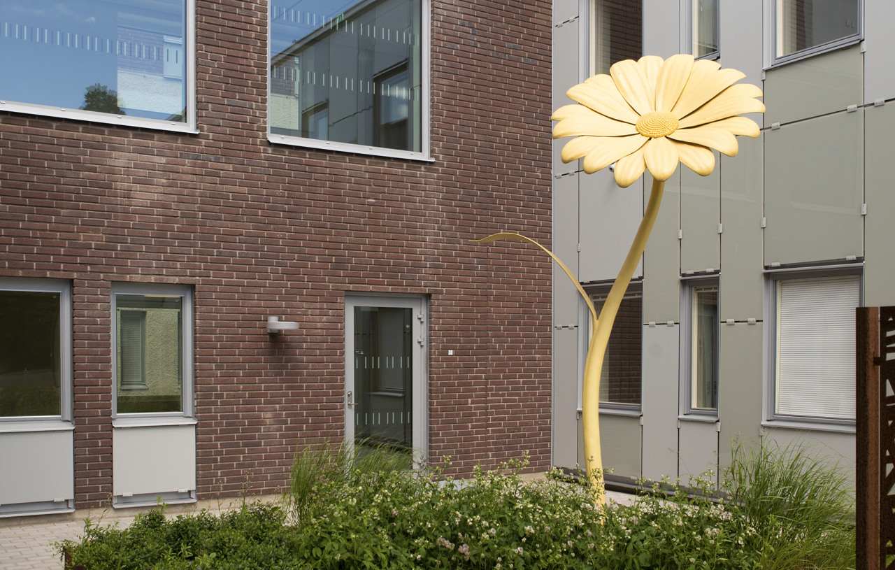 Innerg&aring;rd med konstf&ouml;rem&aring;l, en stor gul blomma. 